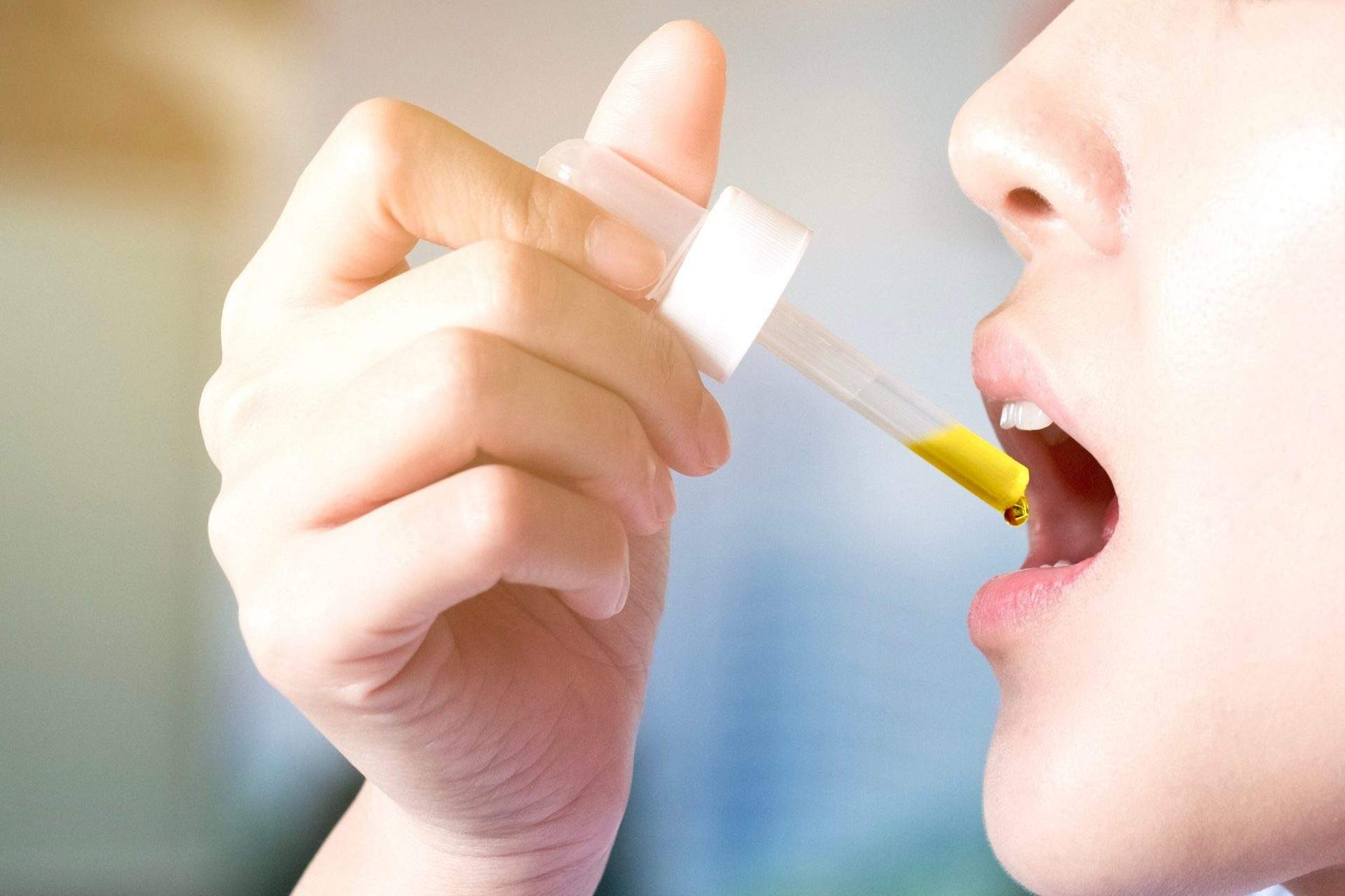 une femme prenant CBD huile sous sa langue avec une pipette