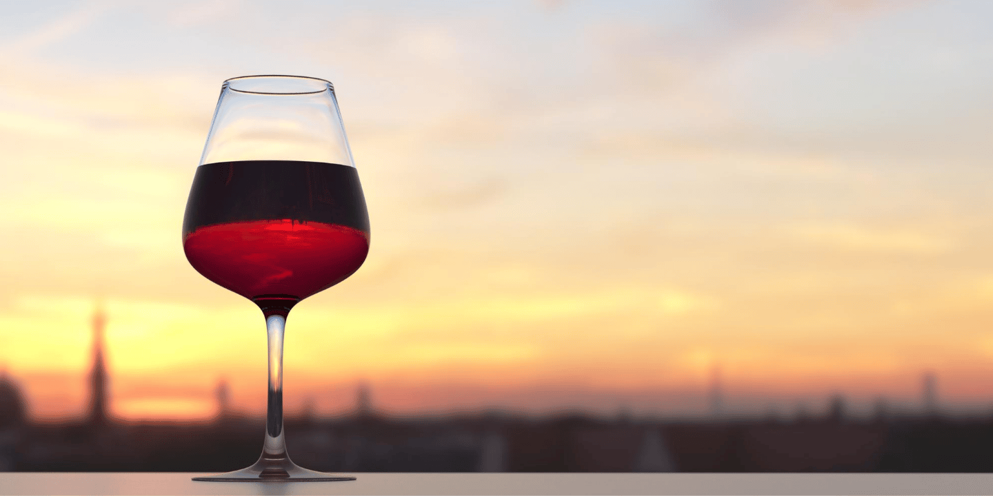 A glass of red wine with a sunset in the background. Resveratrol is a compound found in red wine.