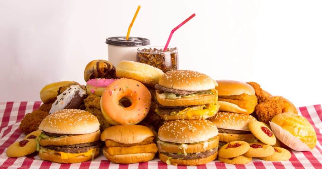 a stack of fast food and soda. Food plays a role in gut health which has a direct effect on arthritis.