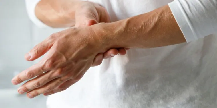 Une personne tenant son poignet qui souffre de douleurs causées par le syndrome du canal carpien.