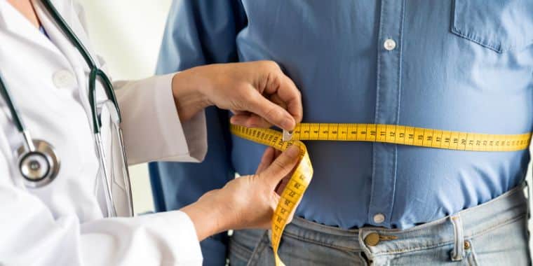 Ein Arzt, der den BMI einer Person misst. Die Suche nach ärztlicher Unterstützung ist ein wichtiger erster Schritt, um Gewicht zu verlieren. Sie können Sie auch darüber beraten CBD Öl und alle Wechselwirkungen mit Medikamenten, die Sie derzeit einnehmen.