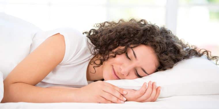 een vrouw die vredig slaapt. Deze afbeelding is om context te geven aan het belang van een goede nachtrust om uw doelen voor gewichtsverlies te helpen.